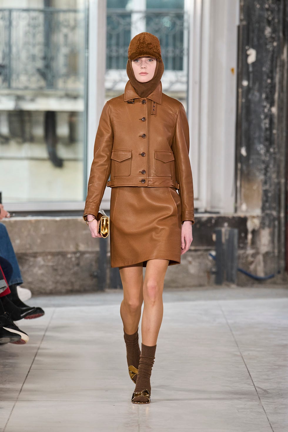 A model walking on a runway wearing a brown leather outfit